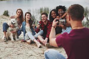 diga queijo. grupo de pessoas faz piquenique na praia. amigos se divertem no fim de semana foto