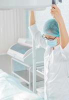 enfermeira segura uma lâmpada cirúrgica foto