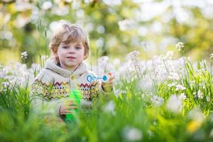 menino feliz no jardim primavera com flores desabrochando brancas foto