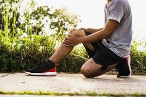 homens feridos por exercício usam as mãos para segurar os joelhos no parque foto