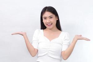 mulher bonita asiática na camisa branca mostra a mão para apresentar algo sobre fundo branco. foto