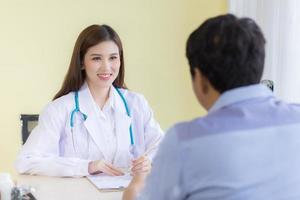 uma bela médica asiática sorriu e perguntou sobre os sintomas. foto