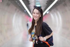 turista bonita asiática, vestindo uma camisa preta, sorriu para um túnel do metrô e carregava uma mochila nas costas. foto