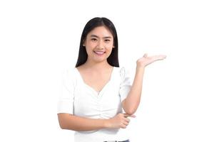 mulher asiática de cabelos longos pretos veste camisa branca e mostra apontar para apresentar algo em fundo branco. foto