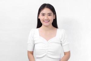mulher bonita asiática com cabelo comprido preto na camisa branca está sorrindo em fundo branco. foto
