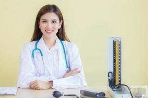 médico de mulher asiática com rosto sorridente, sente-se no escritório no hospital foto