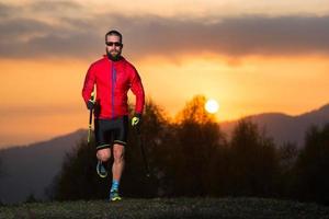 homem atleta praticando caminhada nórdica nas montanhas ao pôr do sol com um céu colorido foto