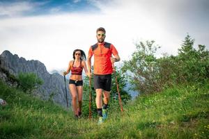 casal desportivo nas montanhas com bastões de caminhada nórdica foto