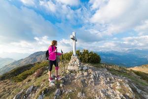 garota solitária no topo de uma montanha com cruz foto