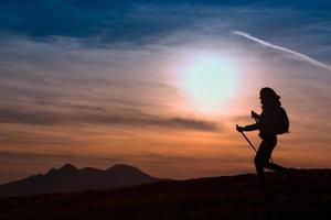 mulher caminhando nas montanhas ao pôr do sol aventura ao ar livre estilo de vida ativo foto