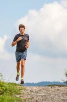 homem jovem atleta corre na estrada de terra foto
