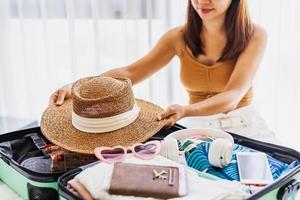 viajante jovem sentado na cama fazendo a mala se preparando para viajar nas férias de verão foto