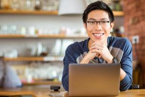 homem asiático positivo em copos com laptop foto