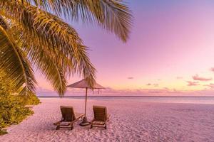 linda praia. cadeiras na praia de areia perto do mar. férias de verão e conceito de férias para o turismo. paisagem tropical inspiradora. cenário tranquilo, praia relaxante, paisagismo tropical foto