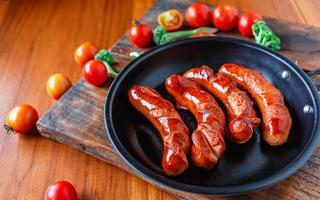 salsichas fritas em uma panela com tomate e brócolis foto