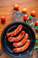 salsichas fritas em uma panela com tomate e brócolis foto