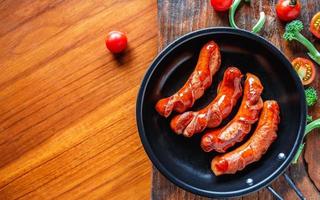 salsichas fritas em uma panela com tomate e brócolis foto