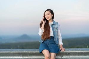 jovem mulher falando com alguém em seu celular enquanto olha para longe com expressão facial feliz. foto