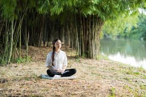 jovem mulher asiática meditando na floresta de bambu foto