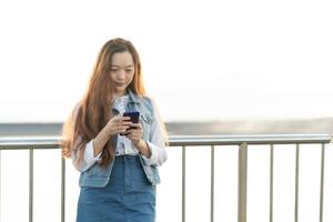 jovem mulher usando smartphone no dedo pressionando ao ar livre, lendo a internet de mídia social, digitando texto ou comprando celular online foto