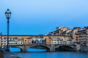 pôr do sol na ponte vecchio - ponte velha - em florença, itália. incrível luz azul antes do anoitecer. foto