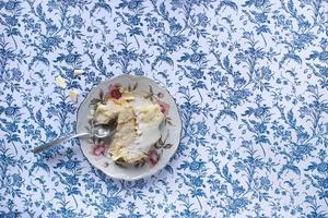 bolo de baunilha com bolo de glacê branco e fatia na mesa azul estampada foto