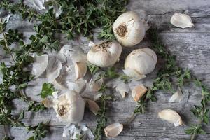 bulbos de alho e talos de orégano na vista superior de madeira rústica foto