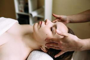 massagista fazendo massagem no rosto de uma mulher no spa. o conceito de procedimentos cosméticos. foto
