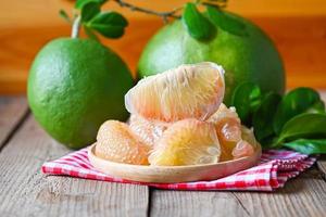 fruta pomelo no fundo da placa de madeira, pomelo verde fresco descascado e folha da árvore pomelo, pummelo, toranja em frutas tropicais de verão na tailândia foto