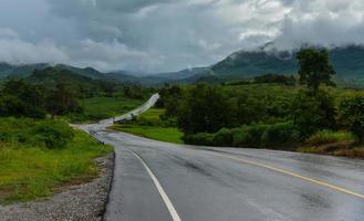 estrada escorregadia curva de estrada molhada para a montanha depois da chuva com cobertura de nuvens de chuva foto