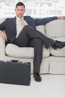 empresário sentado com as pernas cruzadas no sofá foto