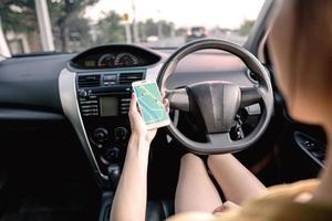 mulher no carro e segurando o celular com mapa de navegação gps foto