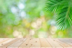 tampo de mesa de madeira vazio e folha de palmeira verde bokeh foto