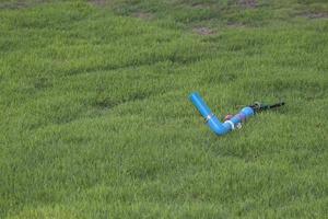 aspersor de rega pronto a instalar em relvados verdes na tranquila zona rural à beira do lago, desenvolvendo-se num abrigo relaxante. foto