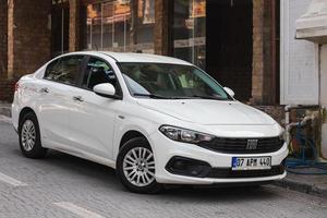 side turkey 18 de fevereiro de 2022 white fiat egea está estacionando na rua em um dia de verão contra o pano de fundo de um hotel, parque foto