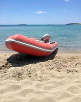 barco vermelho na frente das águas claras em elafonisi, creta, grécia foto