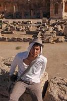 jovem de chapéu em uma antiga ruína romana em baalbek, líbano foto