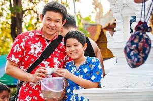 família tailandesa participa de antiga atividade tradicional em um templo durante o festival songkran em chiang mai, norte da tailândia, evento muito famoso da tailândia foto