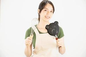 senhora feliz segurando coisas de cozinha sobre fundo de espaço de cópia - conceito de preparação de comida caseira de pessoas foto