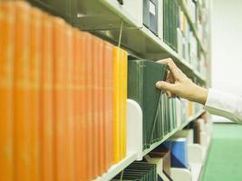 homem está selecionando o livro da estante em uma biblioteca foto