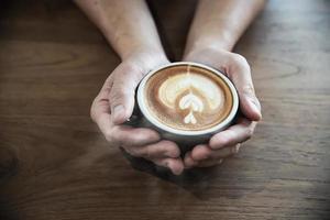 mão segurando uma xícara de café quente - pessoas com conceito de fundo de café foto