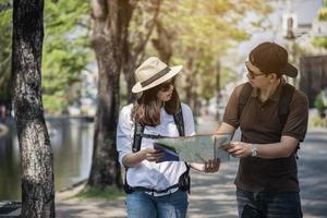 turista de casal de mochila asiática segurando o mapa da cidade atravessando a estrada - conceito de estilo de vida de férias de pessoas de viagem foto