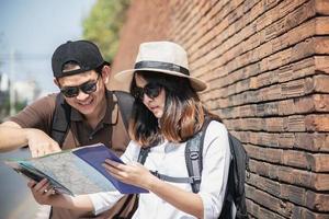 turista de casal de mochila asiática segurando o mapa da cidade atravessando a estrada - conceito de estilo de vida de férias de pessoas de viagem foto