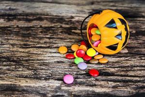 baldes de rosto de abóbora de halloween com doces coloridos dentro de textura de madeira velha foto