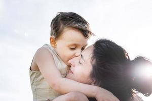 família feliz de mãe e criança caminhando no campo de trigo, abraçando e beijando foto