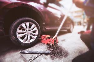 pneu de carro trocado para manutenção na garagem usando macaco hidráulico - conceito de manutenção do carro foto