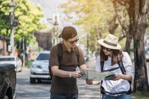 turista de casal de mochila asiática segurando o mapa da cidade atravessando a estrada - conceito de estilo de vida de férias de pessoas de viagem foto