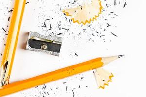 lápis, apontador de metal e aparas de lápis sobre fundo branco. imagem horizontal. foto