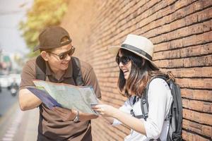 turista de casal de mochila asiática segurando o mapa da cidade atravessando a estrada - conceito de estilo de vida de férias de pessoas de viagem foto