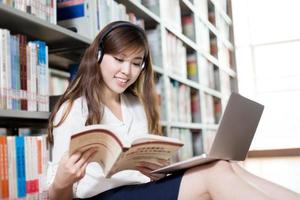 bela aluna asiática estudando na biblioteca com o laptop
